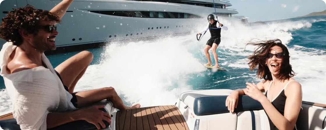 Guests enjoying the sea from a luxury yacht - wakeboarding near the vessel
